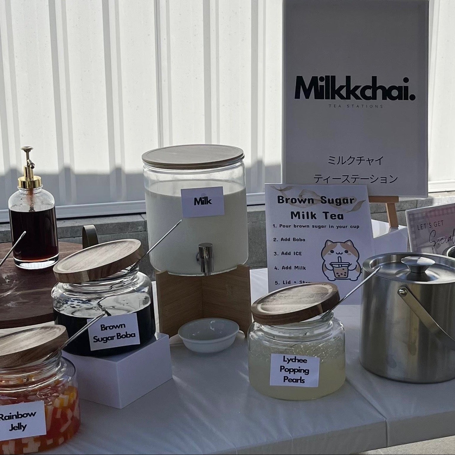 Aesthetic table setup with various jars and a milk dispenser as part of the Bubble Tea DIY station. 